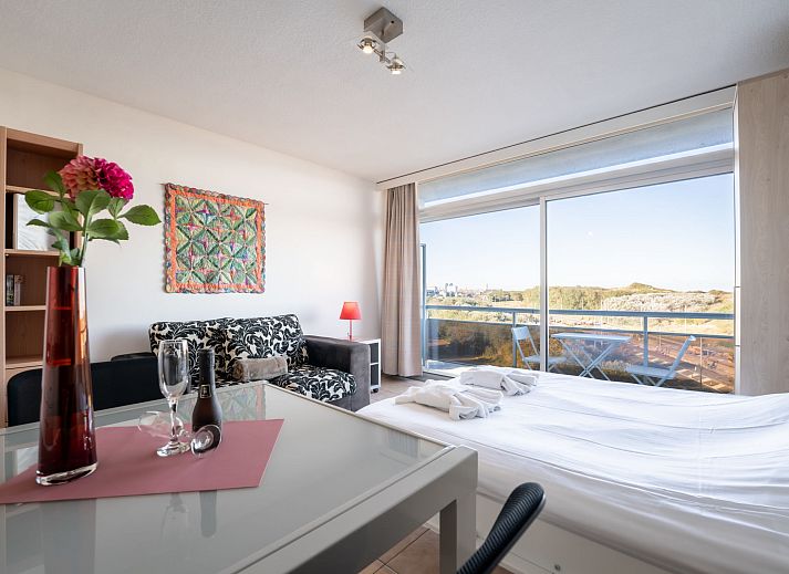 Bright living room of Apartment Studio 62-705 in Bredene, Belgian coast, overlooking dunes and modern furnishings.