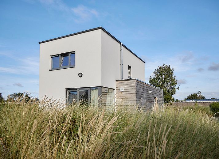 Vrijstaande woning in Bredene, Belgische kust: modern vakantiehuis met terras en ligstoelen, omringd door duinen en natuur.