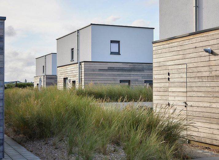 Vrijstaande woning in Bredene, Belgische kust: modern vakantiehuis met terras en ligstoelen, omringd door duinen en natuur.