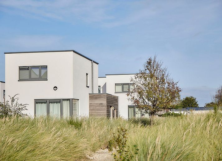 Vrijstaande woning in Bredene, Belgische kust: modern vakantiehuis met terras en ligstoelen, omringd door duinen en natuur.