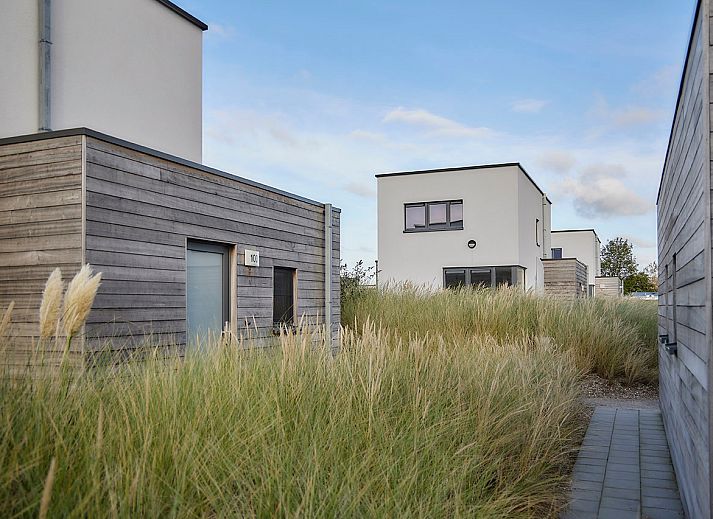 Vrijstaande woning in Bredene, Belgische kust: modern vakantiehuis met terras en ligstoelen, omringd door duinen en natuur.