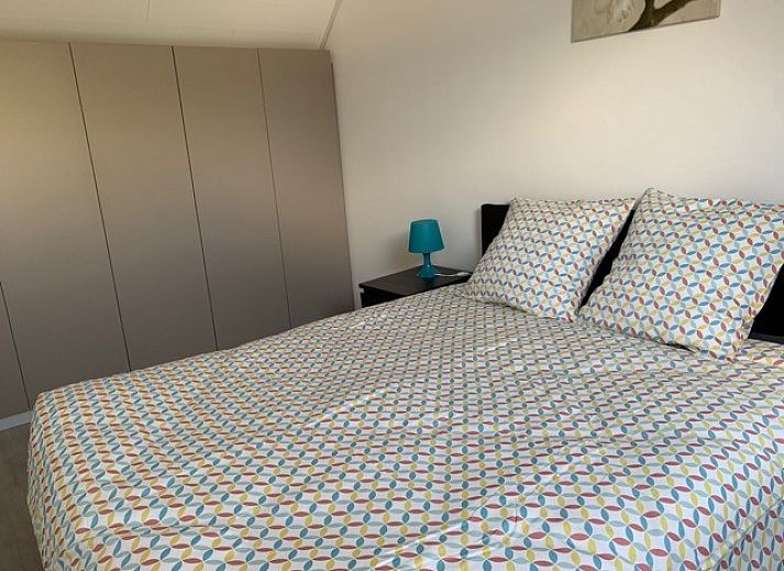 Ruime eetkamer met houten tafel in Vakantiehuis RUST, Middelkerke, Belgische kust, uitzicht op kleurrijke muurschildering.