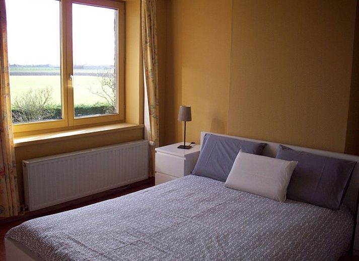 Gezellige binnenruimte van vakantiehuis Cobergh in Veurne met rode bank en houten details.