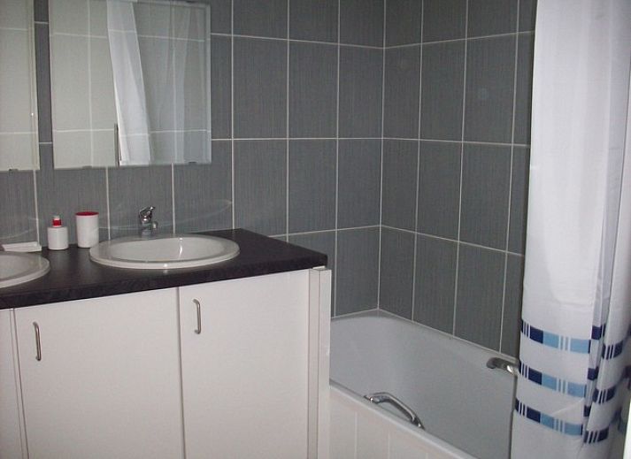 Gezellige binnenruimte van vakantiehuis Cobergh in Veurne met rode bank en houten details.