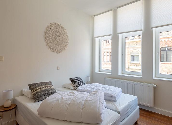 Rustieke binnenplaats van vakantiehuis Notre Dame in Nieuwpoort, Belgische kust, met charmante zithoek en decoratieve potten.