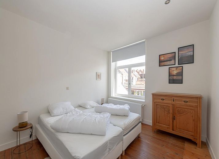 Sfeervolle slaapkamer in vakantiehuis Notre Dame, Nieuwpoort, Belgische kust, met twee bedden en een bureau onder een dakraam.