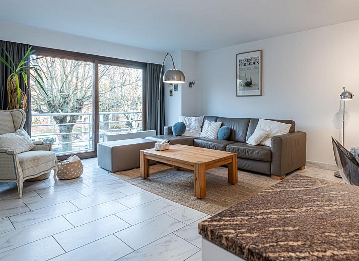 Gezellige woonkamer in vakantiehuis Reigersnest, Nieuwpoort, Belgische kust, met comfortabele zithoek en uitzicht op groene omgeving.