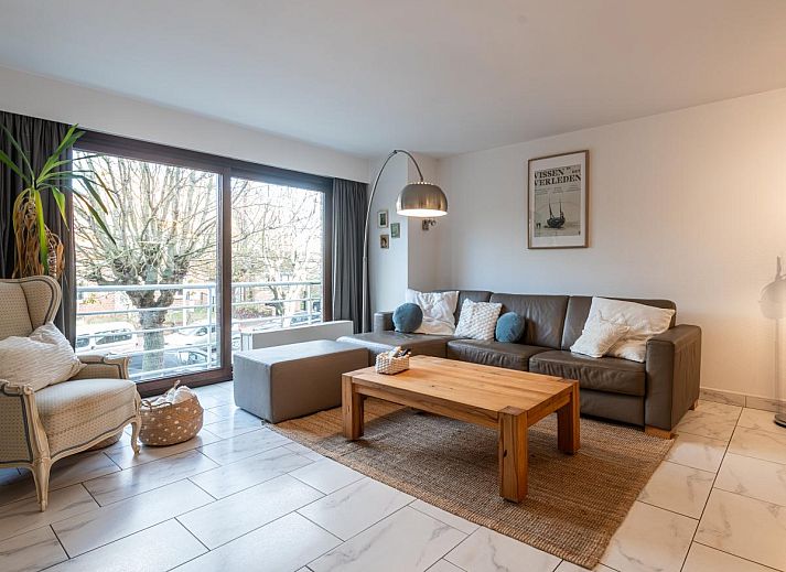 Gezellige woonkamer in vakantiehuis Reigersnest, Nieuwpoort, Belgische kust, met comfortabele zithoek en uitzicht op groene omgeving.