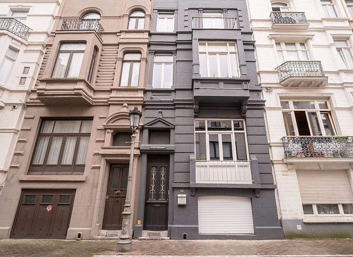 Gezellig terras bij Appartement Villa George in Oostende, Belgische kust, met comfortabele zitplek en groene accenten.