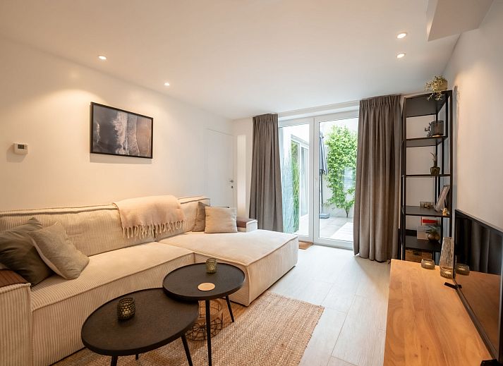 Gezellig terras bij Appartement Villa George in Oostende, Belgische kust, met comfortabele zitplek en groene accenten.