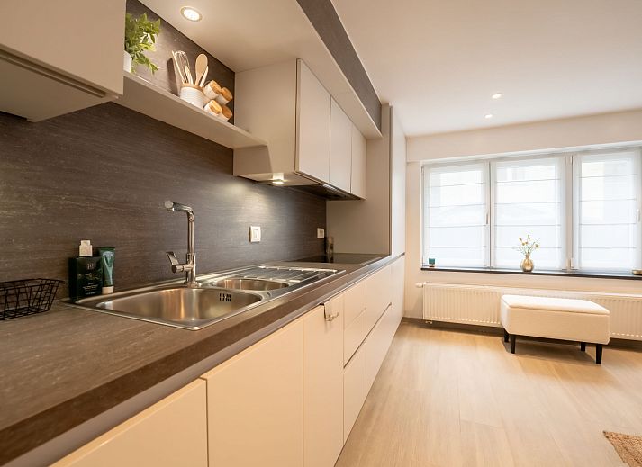 Gezellig terras bij Appartement Villa George in Oostende, Belgische kust, met comfortabele zitplek en groene accenten.