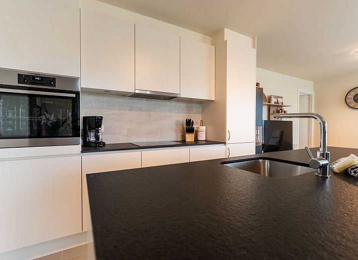 Lichte en ruime woonkamer van Appartement THe Waves in Oostende, Belgische kust, met moderne keuken en eethoek voor een comfortabel verblijf.