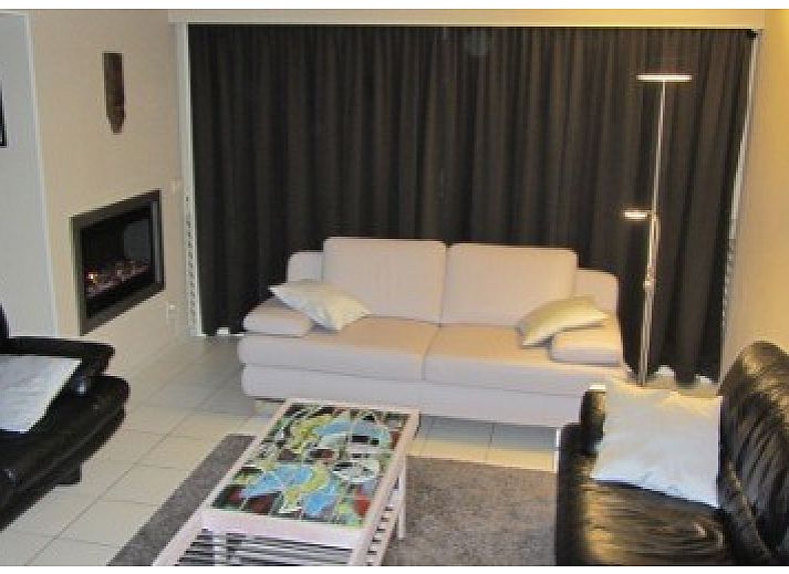Gezellige woonkamer van De Viebarke vakantiehuis in Nieuwpoort-Bad, Belgische kust, met uitzicht op de groene tuin.