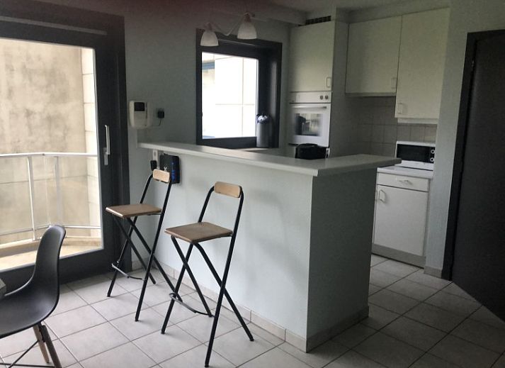Dining area in Topaze apartment, De Panne, Belgian coast, with large windows and wooden closet.