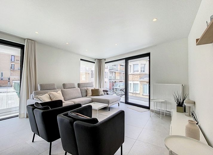 Modern living room in Apartment 'Asterias', De Panne, with comfortable seating area and large windows.