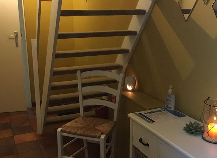 Gemuetliches Wohnzimmer des Ferienhauses Windekind mit Blick auf die Felder in De Panne, belgische Kueste, mit Kamin und gemuetlicher Sitzecke.