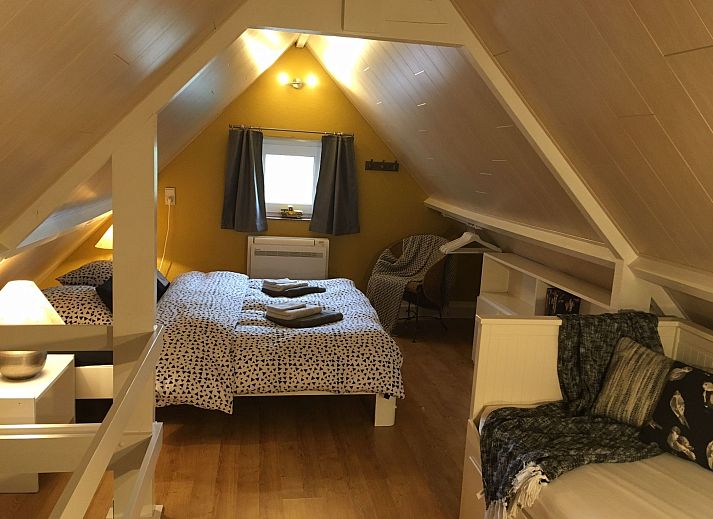 Gemuetliches Wohnzimmer des Ferienhauses Windekind mit Blick auf die Felder in De Panne, belgische Kueste, mit Kamin und gemuetlicher Sitzecke.