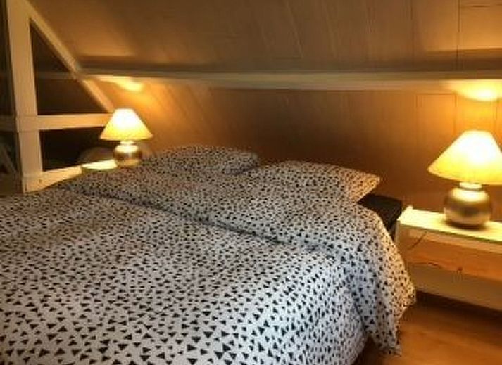 Gemuetliches Wohnzimmer des Ferienhauses Windekind mit Blick auf die Felder in De Panne, belgische Kueste, mit Kamin und gemuetlicher Sitzecke.