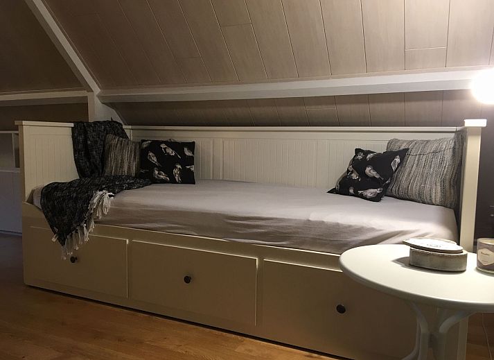 Gemuetliches Wohnzimmer des Ferienhauses Windekind mit Blick auf die Felder in De Panne, belgische Kueste, mit Kamin und gemuetlicher Sitzecke.