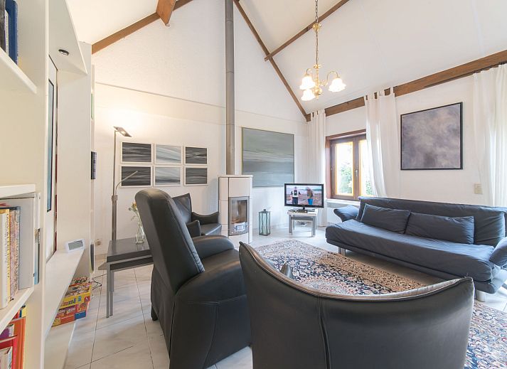 Gezellige woonkamer in Vakantiehuis V54 met open haard en comfortabele zithoek, gelegen in De Haan aan de Belgische kust.