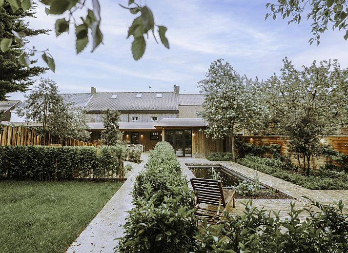 Gezellige woonkamer in Vakantiehuis Huyze Ter Bercken in De Haan, Belgische kust, met moderne inrichting en uitzicht op de tuin.
