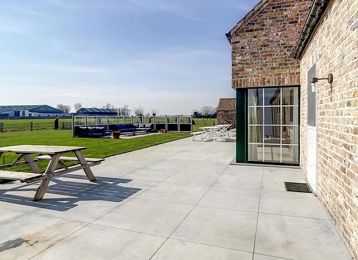 Eetkamer met lange tafels in Hoeve Langhof vakantiehuis, De Haan, ideaal voor groepsdiners.