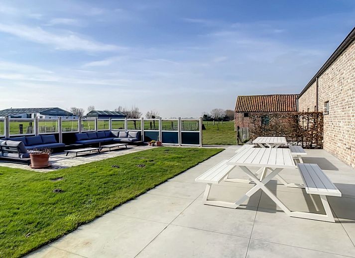Eetkamer met lange tafels in Hoeve Langhof vakantiehuis, De Haan, ideaal voor groepsdiners.