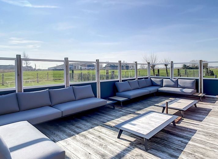 Eetkamer met lange tafels in Hoeve Langhof vakantiehuis, De Haan, ideaal voor groepsdiners.