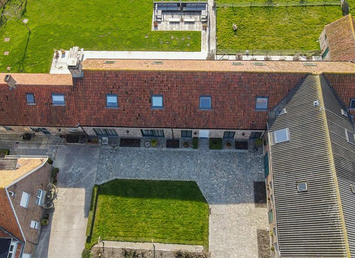 Eetkamer met lange tafels in Hoeve Langhof vakantiehuis, De Haan, ideaal voor groepsdiners.