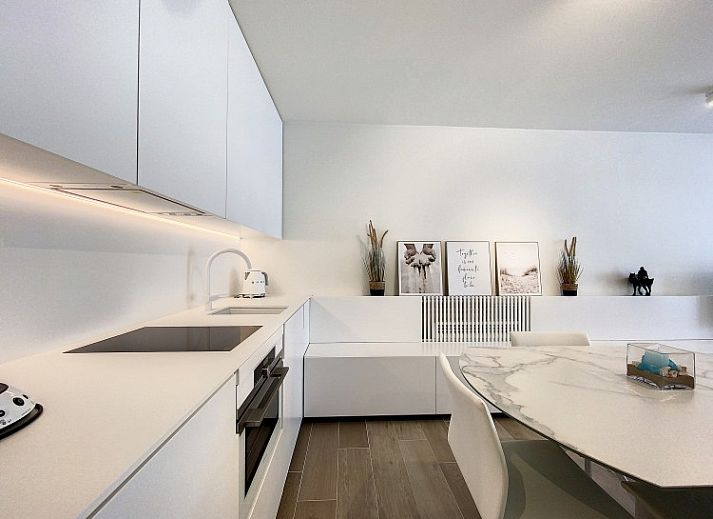 Moderne woonkamer van Studio 'De Zandloper' in Oostduinkerke-bad, Belgische kust, met comfortabele witte bank.