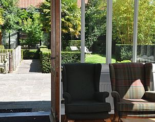 Sunny veranda of Balsamboom Brugge in Bruges, West Flanders overlooking green garden.