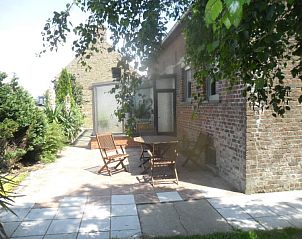 Zonnig terras bij Den Anker vakantiehuis in Houthulst, West-Vlaanderen omgeven door groen.