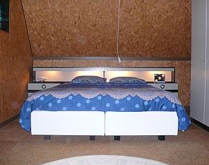 Ruime slaapkamer met blauw beddengoed in Den Anker vakantiewoning in Houthulst, West-Vlaanderen.