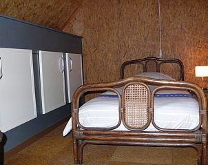 Knusse slaapkamer met houten details in Den Anker vakantiehuis in Houthulst, West-Vlaanderen.