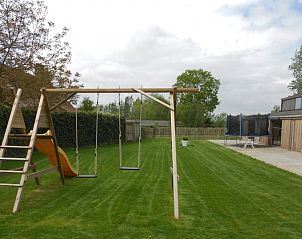 Ruime schuur bij Hof ter Harte vakantiehuis, Ieper, West-Vlaanderen met stapels hout en bloeiende planten.