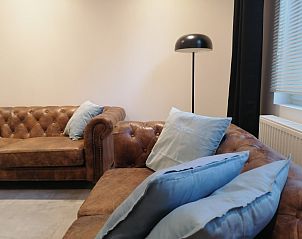 Comfortabele zithoek met leren bank en kussens in THE FRONT DOOR N28, vakantieverblijf in Ieper, West-Vlaanderen.
