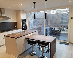 Moderne keuken met kookeiland en barstoelen in THE FRONT DOOR N28, vakantiehuis in Ieper, West-Vlaanderen.