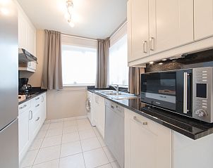 Modern kitchen in Holiday Home Boonenhove No.57 in De Haan, West Flanders, Belgium, with sleek white cabinets and ample workspace.