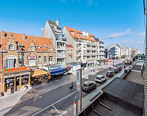 View from Azcona Two vacation home in Koksijde, Belgium, with charming street full of stores and historic architecture on sunny day.
