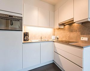 Moderne Kche im Ferienhaus De Dijk sixth, Koksijde, Belgien, mit schlichten weien Schrnken und Einbaugerten.