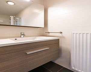 Modernes Badezimmer im Ferienhaus De Dijk sixth, Koksijde, Westflandern, Belgien, mit stilvollem Waschbecken und Spiegel.