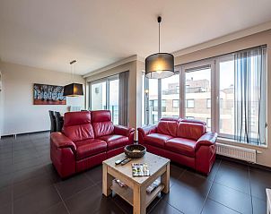 Gemtliches Wohnzimmer im sechsten Ferienhaus De Dijk, Koksijde, mit bequemen roten Sofas und viel Tageslicht.