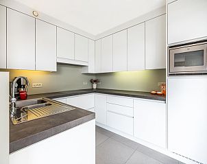 Moderne Kche in Tinou Ferienhaus im Erdgeschoss in Koksijde, Westflandern, mit schlichten weien Schrnken und grozgigen Arbeitsflchen.