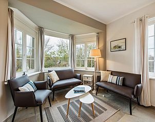 Gemtliches Wohnzimmer des Ferienhauses Le Cozy in Koksijde, Westflandern, Belgien mit bequemer Sitzecke und Blick auf die Natur.