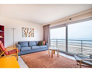 Gemtliches Wohnzimmer im vierten Ferienhaus Les Petrels in Koksijde, Westflandern, mit Panoramablick auf das Meer und bequemer Sitzecke.