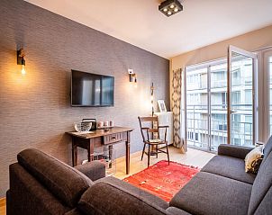 Gemtliches Wohnzimmer im Ferienhaus Neva troisime, Koksijde, mit moderner Einrichtung und Blick auf die stdtische Umgebung in Westflandern.