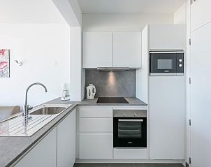 Moderne Kche im Ferienhaus Olbi Premier, Koksijde, Westflandern, mit schlichten weien Schrnken und modernen Gerten.