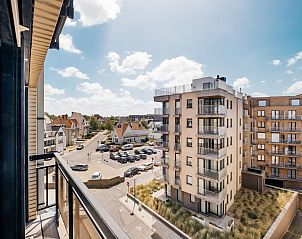 Blick vom Balkon des Ferienhauses Prs de la plage in Koksijde, Westflandern, mit modernen Wohnungen und blauem Himmel.