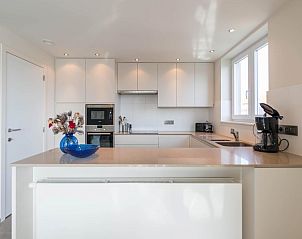 Moderne Kche im Ferienhaus Bon Accueil second in Koksijde, Westflandern, Belgien, mit schlichten weien Schrnken und viel natrlichem Licht.