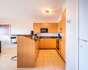 Modern kitchen in vacation home Paco fourth, Koksijde, West Flanders. Spacious interior space with wooden cabinets and tiled floor.